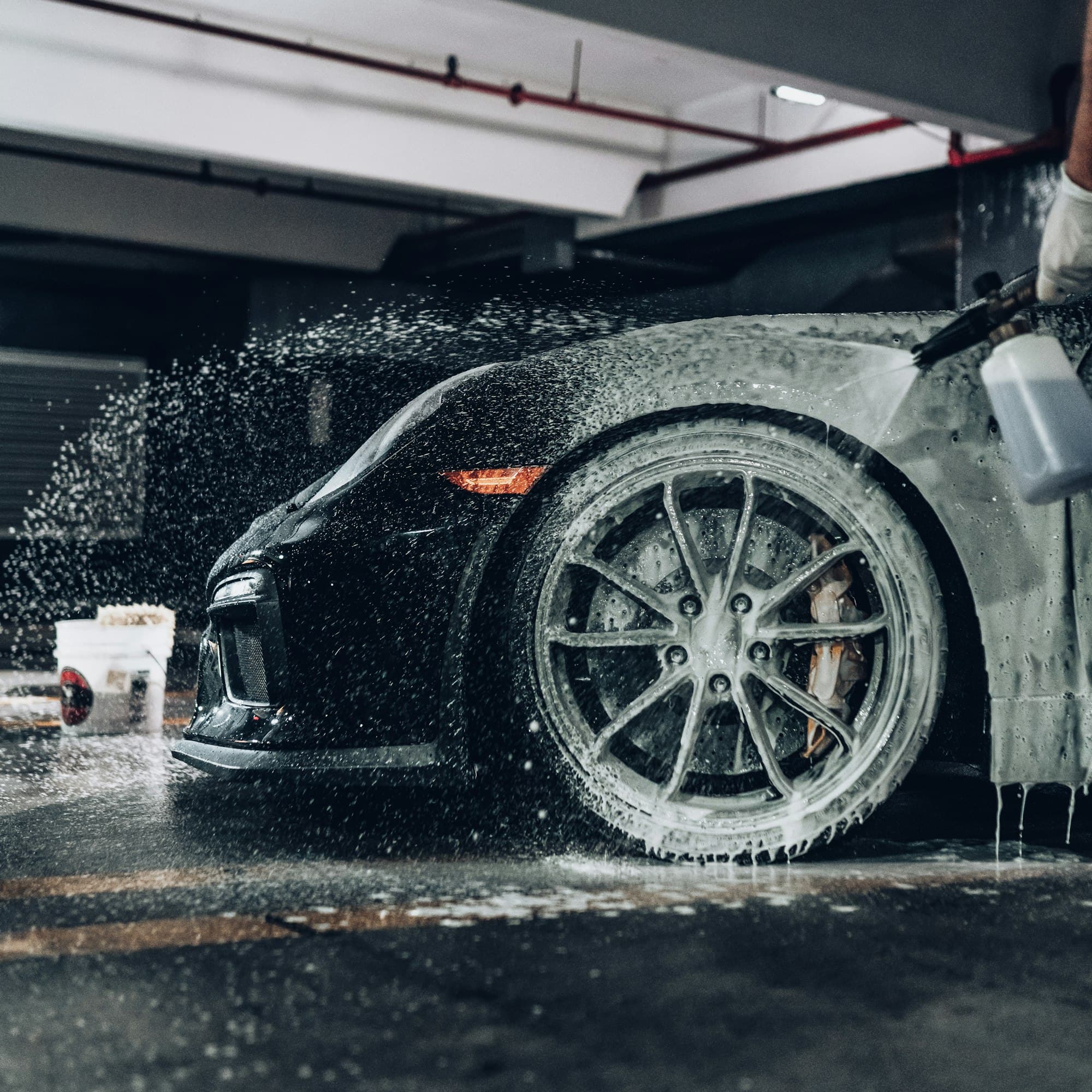 Foam pre-wash being sprayed onto a black sports car