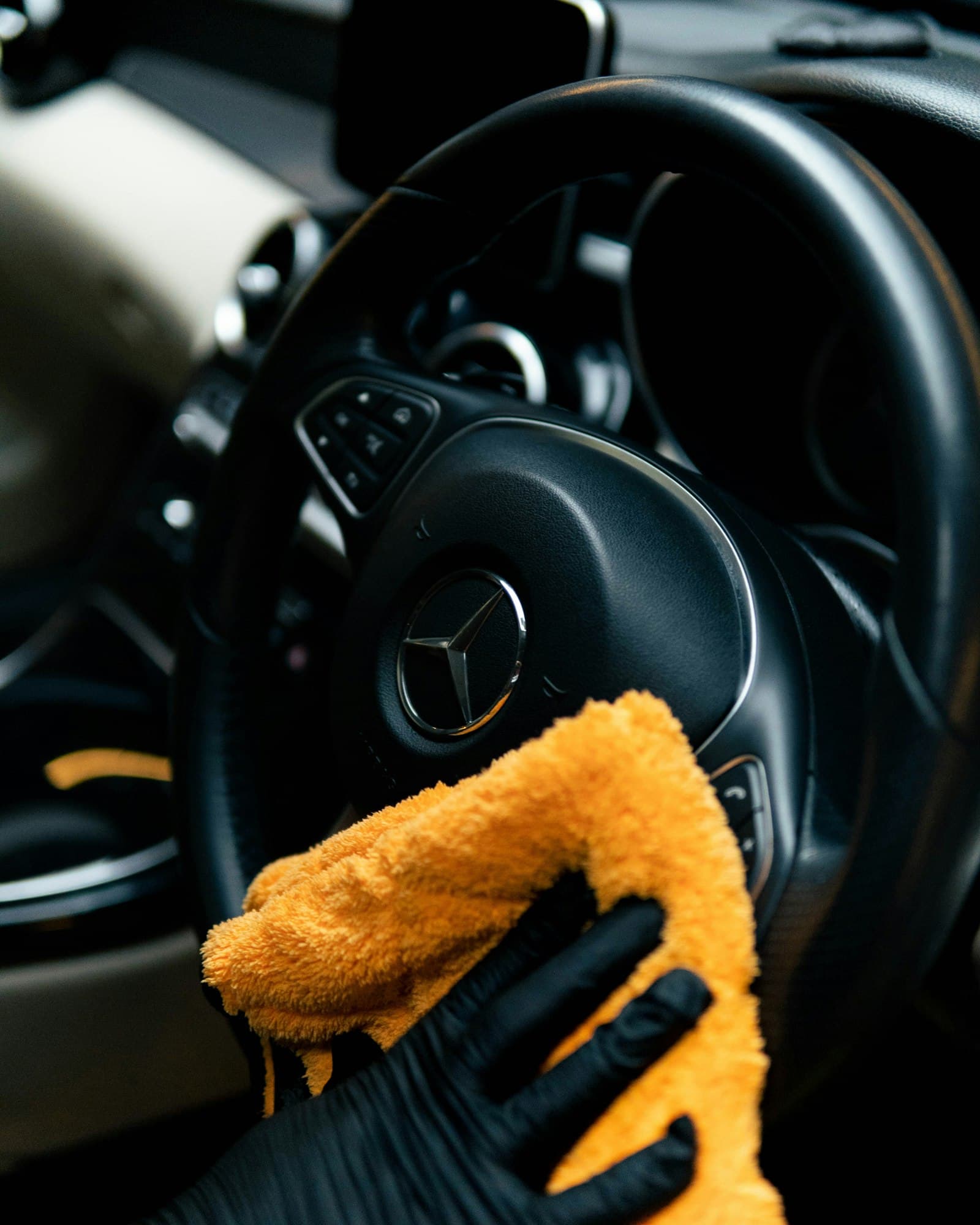 Wiping down a steering wheel and dashboard during an interior detail