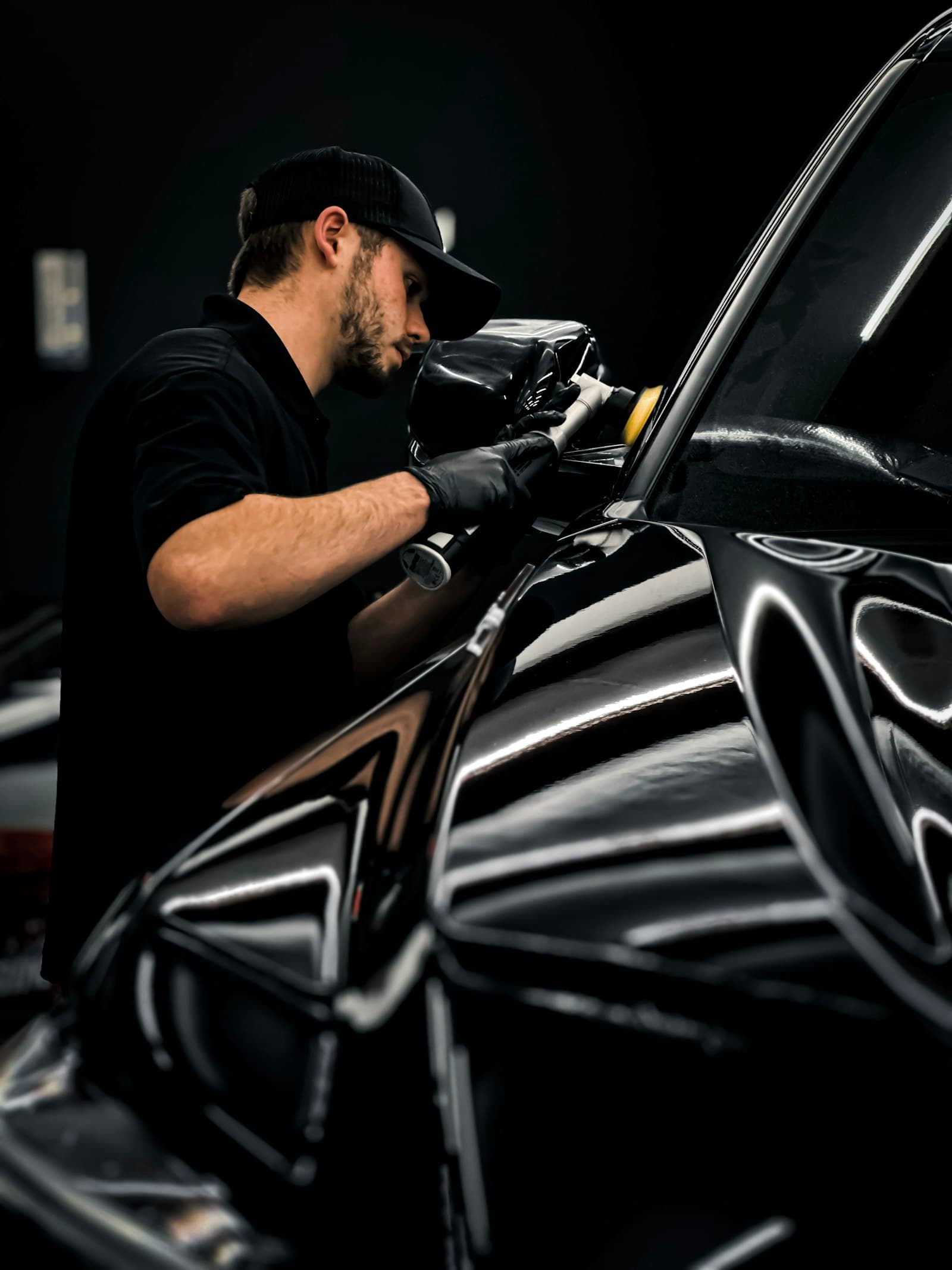 Detailer working on a glossy black car's paint
