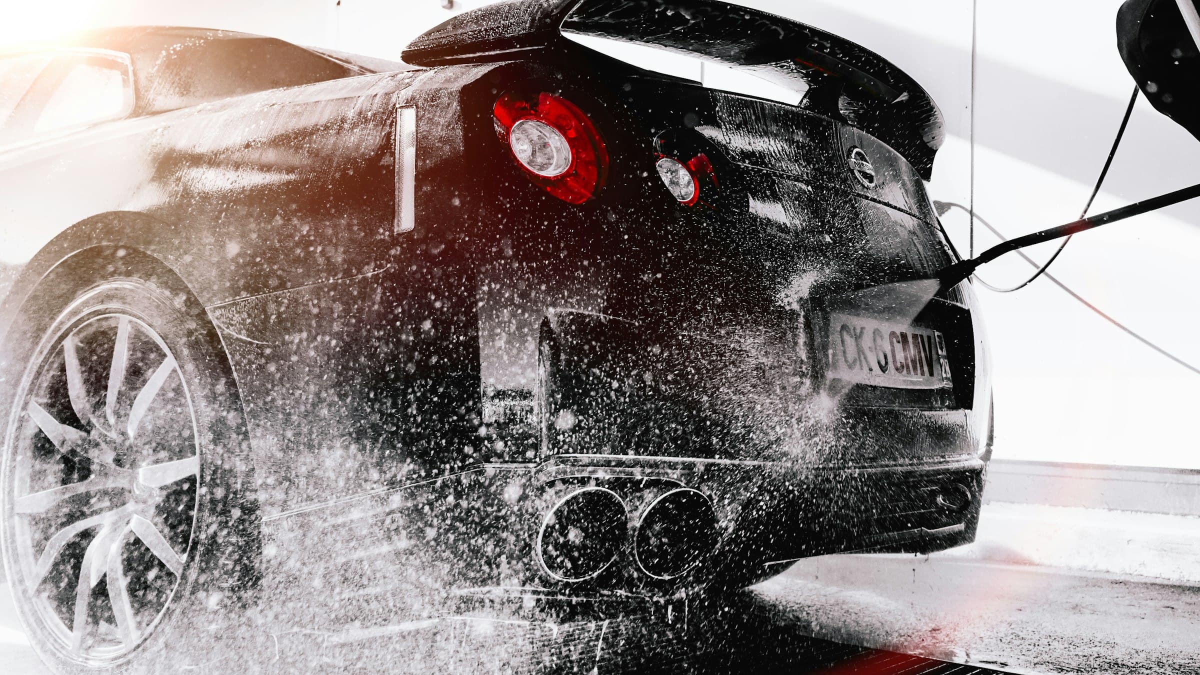 Black sports car being rinsed during a detail
